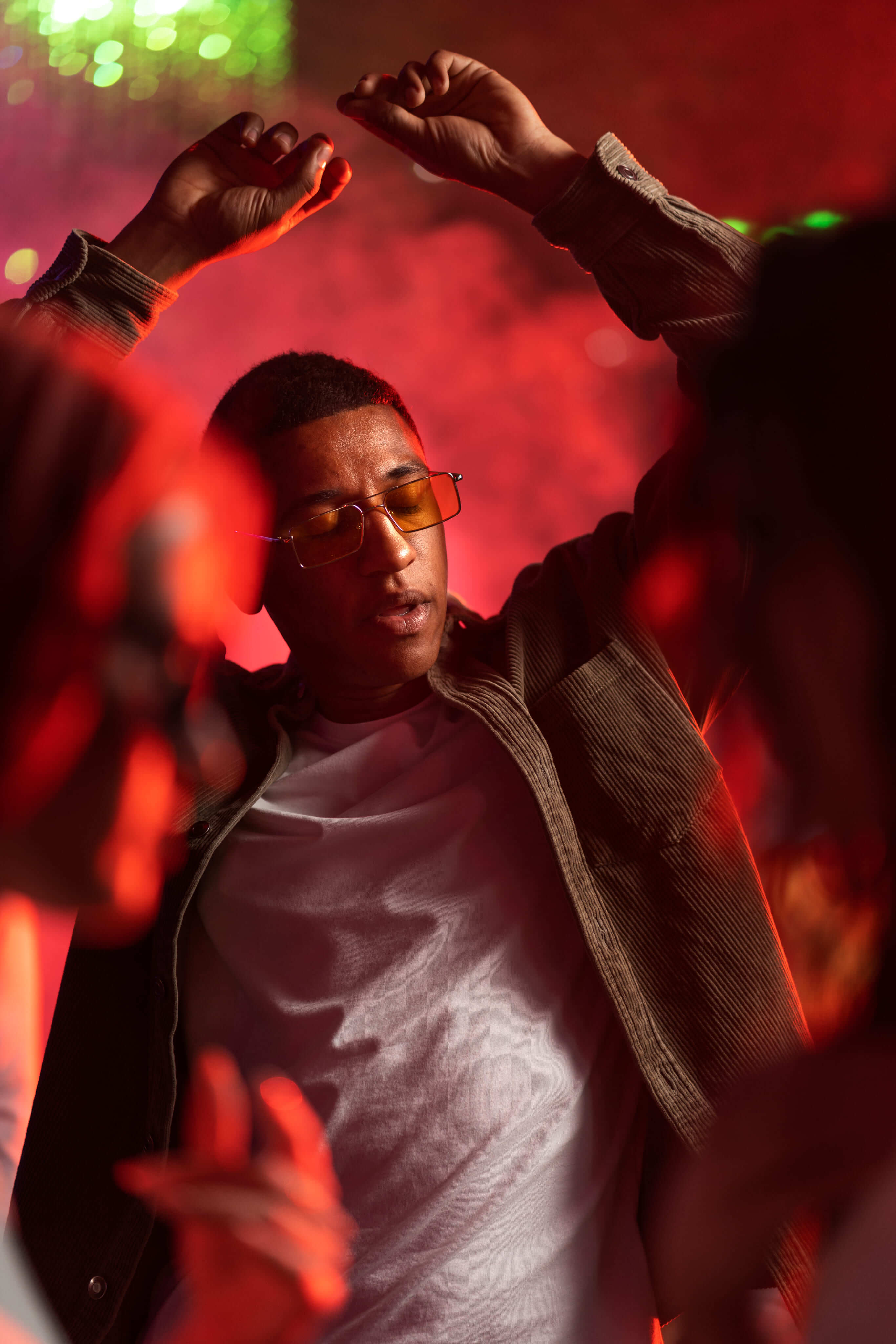Event guest wearing tinted glasses under red stage lights